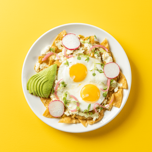 Chilaquiles Verde with sunny up eggs and avocado