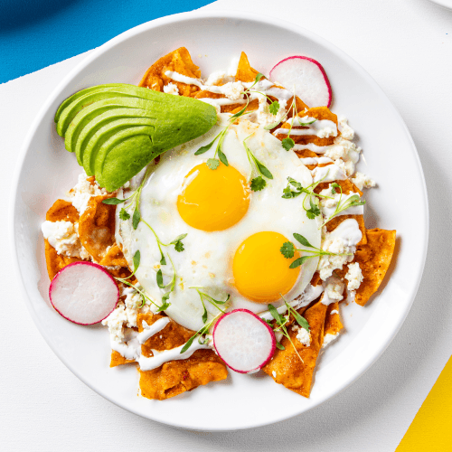 Chilaquiles Rojos topped with avocado and radishes